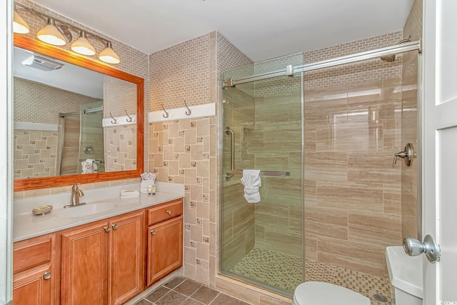 bathroom with a stall shower, vanity, toilet, and tile patterned floors