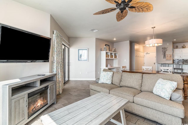 living area with recessed lighting, visible vents, a ceiling fan, a glass covered fireplace, and baseboards