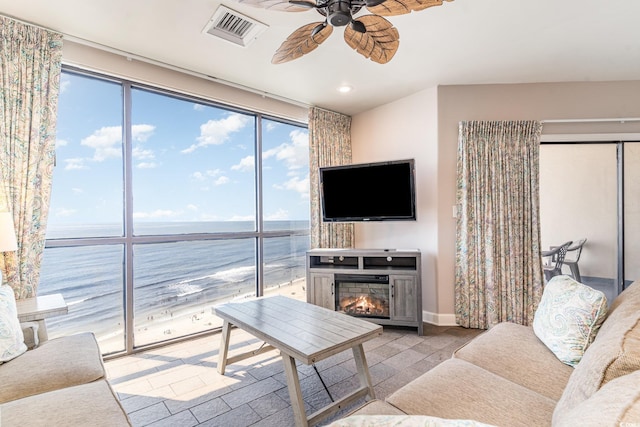 living area featuring a lit fireplace, visible vents, and a ceiling fan