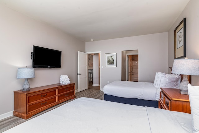 bedroom featuring ensuite bathroom, wood finished floors, and baseboards