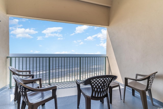 balcony with a water view and a view of the beach