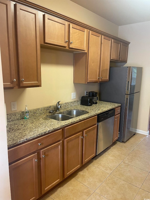 kitchen with sink, stainless steel dishwasher, light stone counters, and light tile patterned flooring