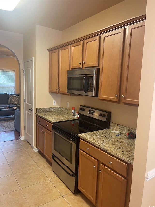 kitchen with light stone counters, appliances with stainless steel finishes, and light tile patterned flooring