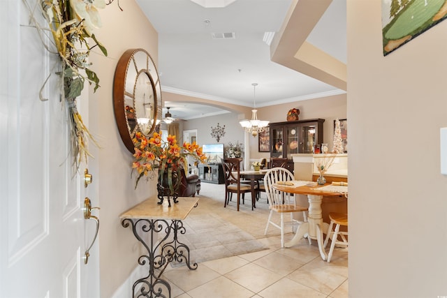 tiled entryway featuring a notable chandelier and ornamental molding