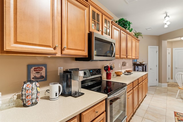 kitchen with track lighting, light tile patterned floors, and stainless steel appliances