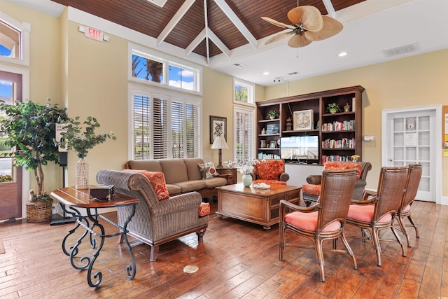 living room featuring wood-type flooring, beam ceiling, and ceiling fan