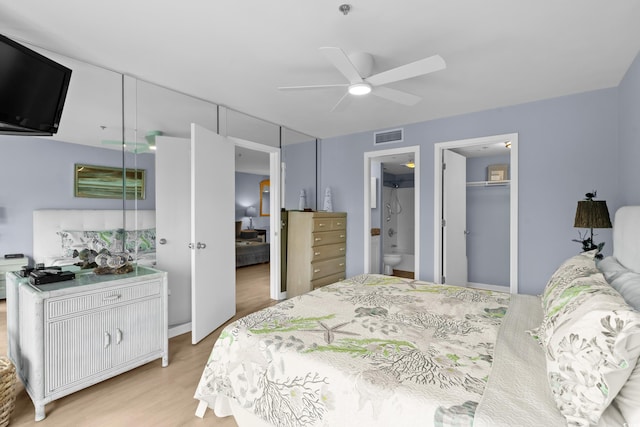 bedroom featuring ceiling fan, light hardwood / wood-style flooring, ensuite bathroom, a walk in closet, and a closet