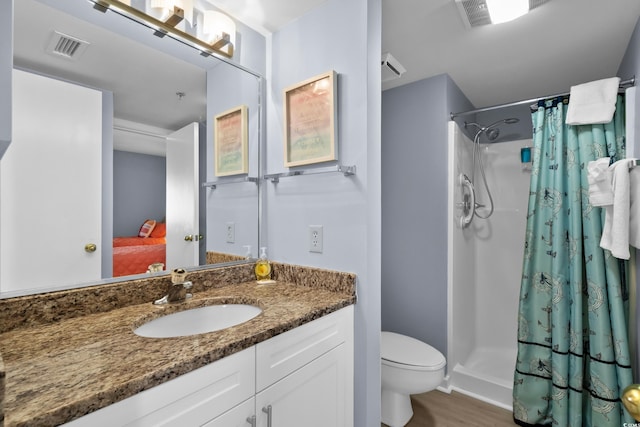 bathroom with toilet, hardwood / wood-style floors, vanity, and walk in shower