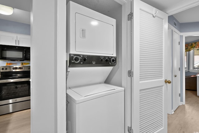 washroom with stacked washer and dryer and light hardwood / wood-style floors