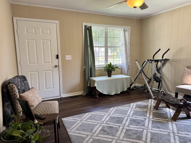 workout room with ceiling fan, wooden walls, dark hardwood / wood-style floors, and ornamental molding