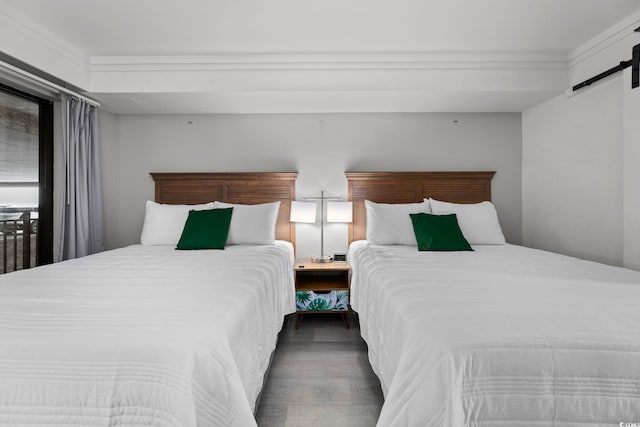 bedroom featuring ornamental molding, dark wood-type flooring, and a barn door