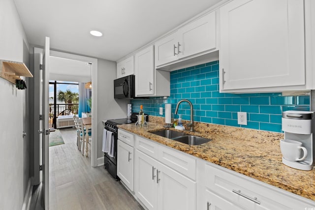 kitchen featuring black appliances, white cabinetry, and light hardwood / wood-style flooring