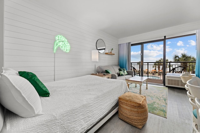 bedroom featuring access to outside, wood walls, and hardwood / wood-style floors