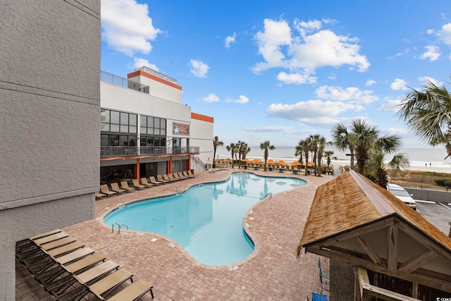 view of pool featuring a water view and a patio area