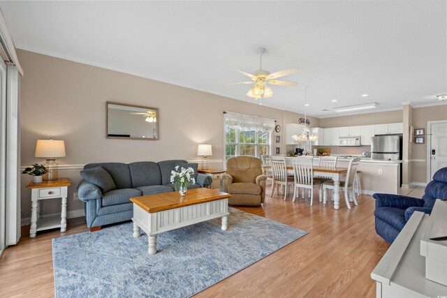 living room with light hardwood / wood-style flooring, ceiling fan with notable chandelier, and ornamental molding