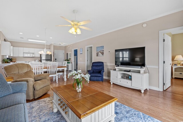 living room with ceiling fan, light wood-type flooring, and crown molding