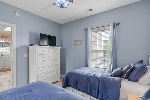 bedroom featuring light tile patterned floors, ceiling fan, and ensuite bathroom