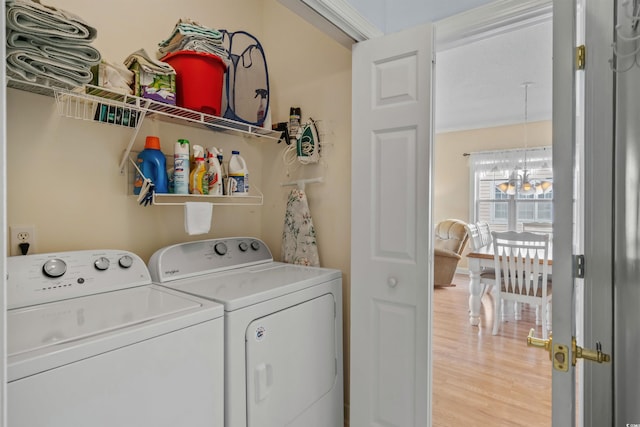 washroom featuring light wood-type flooring, a chandelier, and washer and clothes dryer