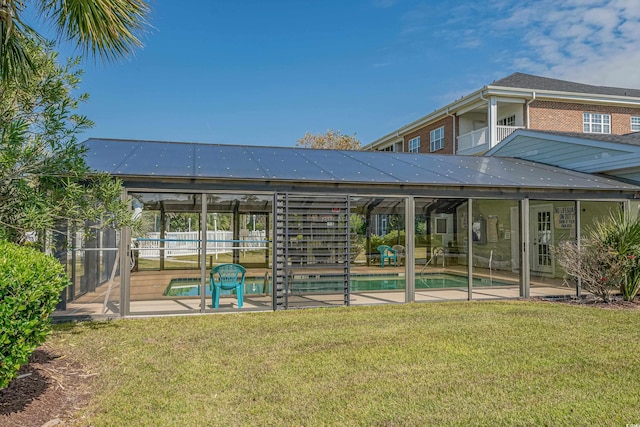 rear view of property featuring a lanai, a balcony, a fenced in pool, a patio area, and a lawn