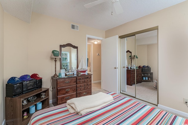 bedroom featuring ceiling fan, light carpet, a textured ceiling, and a closet