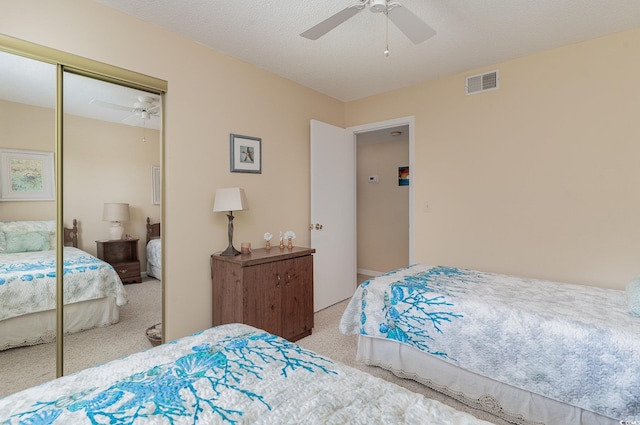 carpeted bedroom with a textured ceiling, a closet, and ceiling fan