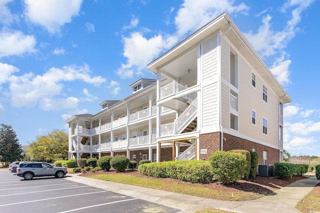 view of property with central air condition unit and uncovered parking