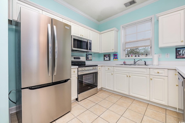 kitchen with sink, ornamental molding, appliances with stainless steel finishes, light tile patterned floors, and white cabinets