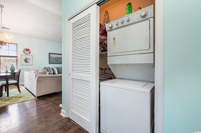 laundry area with dark hardwood / wood-style flooring, stacked washer and clothes dryer, and a chandelier