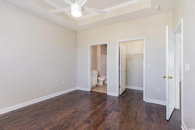 unfurnished bedroom with a closet, baseboards, connected bathroom, wood finished floors, and a walk in closet