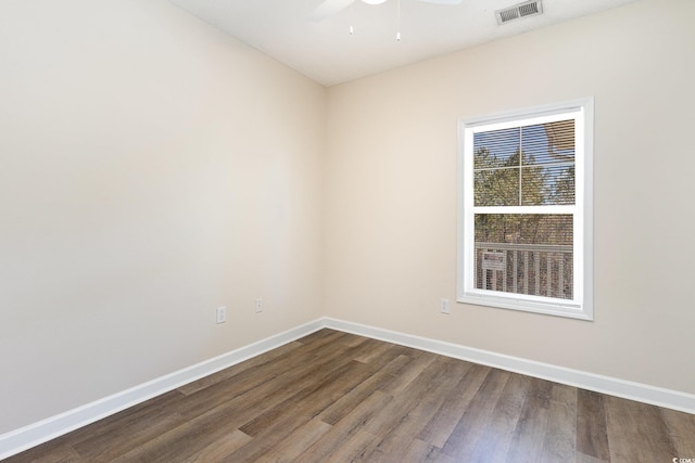 spare room featuring baseboards, visible vents, ceiling fan, and dark wood-style floors