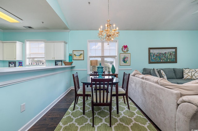 dining room with crown molding, dark wood-type flooring, an inviting chandelier, and a healthy amount of sunlight