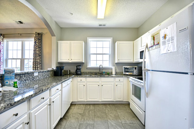 5801 Oyster Catcher Dr Unit 434, North Myrtle Beach, SC 29582 - kitchen featuring white appliances, white cabinetry, arched walkways, a textured ceiling, and dark stone countertops