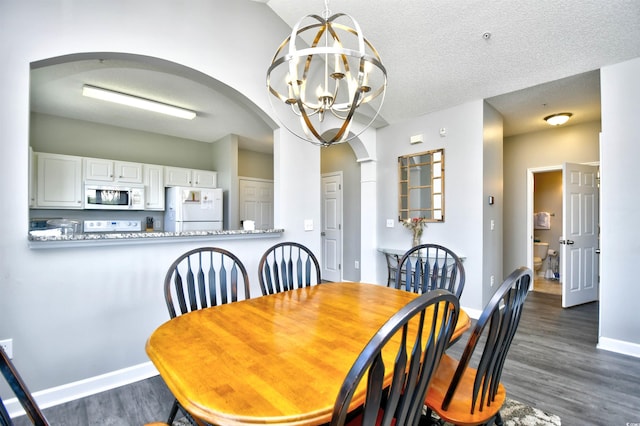 dining space with a textured ceiling, a notable chandelier, and dark wood-type flooring