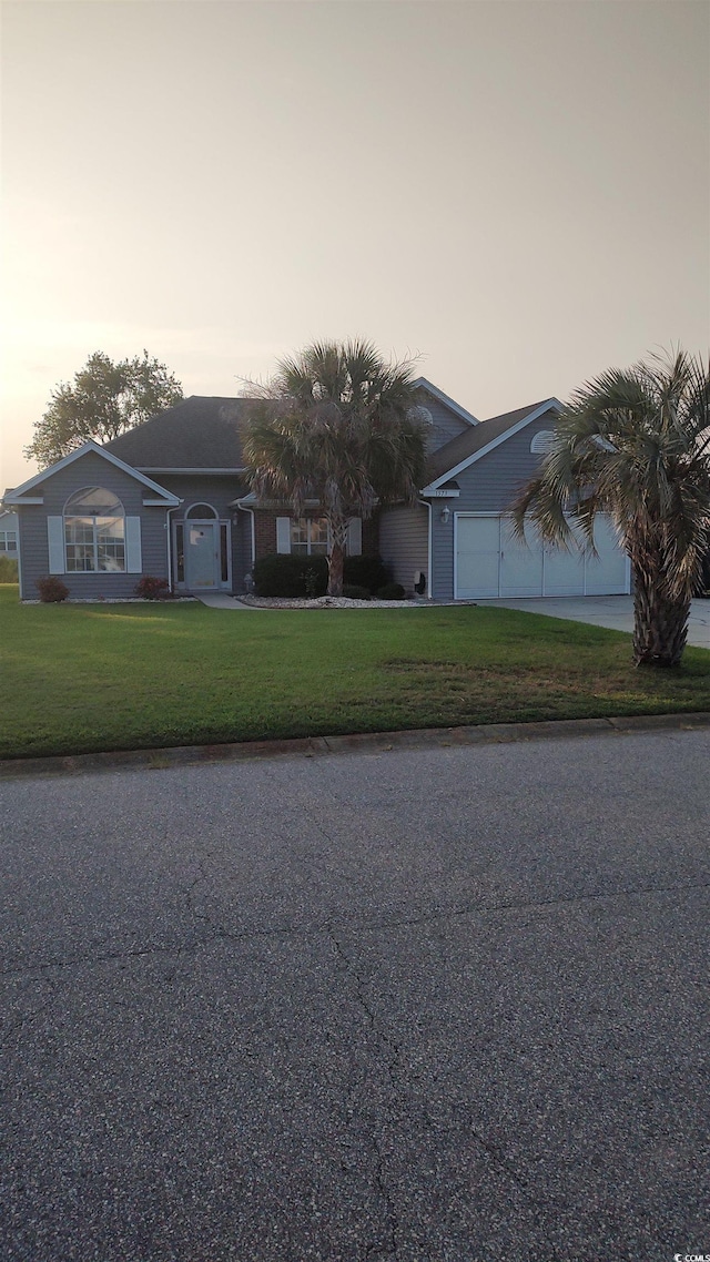 ranch-style house with a garage and a lawn