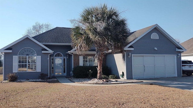 ranch-style home with a shingled roof, concrete driveway, an attached garage, a front yard, and brick siding