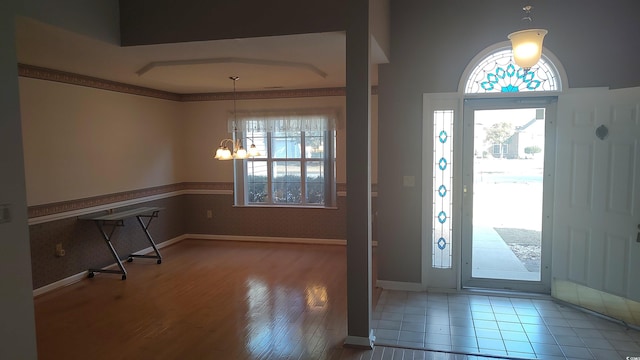 foyer with plenty of natural light, baseboards, a notable chandelier, and wood finished floors