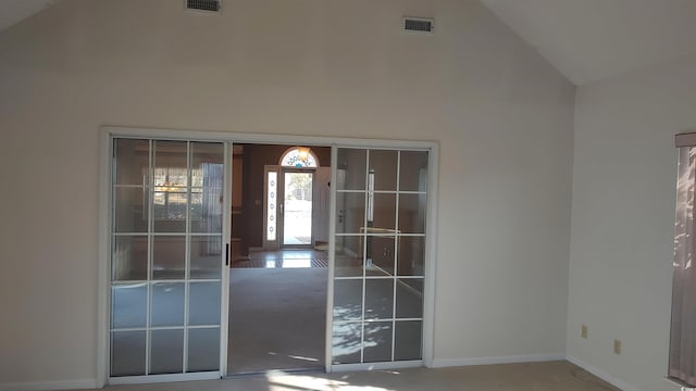 interior space featuring high vaulted ceiling, visible vents, and baseboards