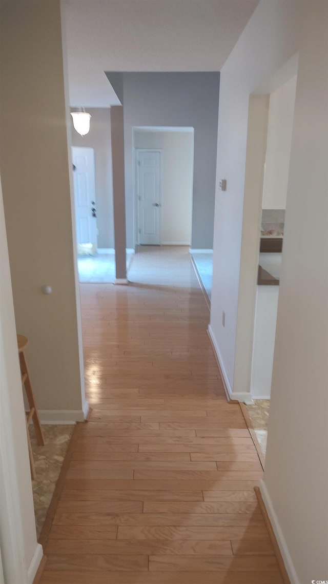 corridor with light wood-style flooring and baseboards