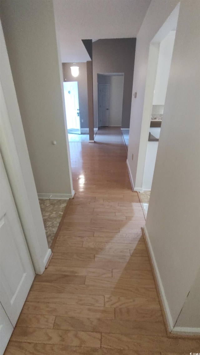 hall featuring light wood finished floors and baseboards