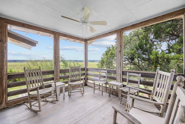 sunroom / solarium with ceiling fan, a wealth of natural light, and a rural view