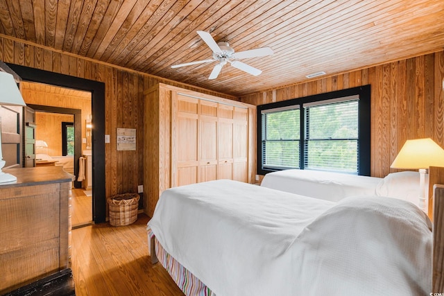 bedroom with a closet, wood-type flooring, wooden walls, and wooden ceiling