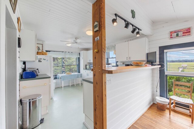 kitchen featuring light wood-type flooring, rail lighting, ceiling fan, vaulted ceiling, and white cabinets