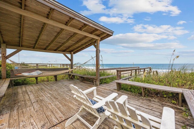 wooden terrace featuring a view of the beach and a water view