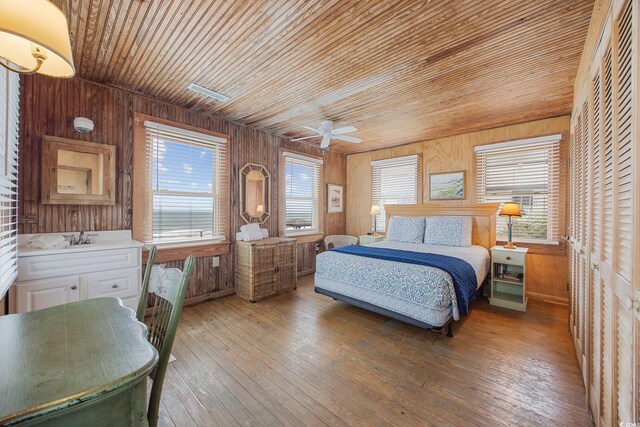 bedroom with wooden walls, wood-type flooring, sink, ceiling fan, and wooden ceiling