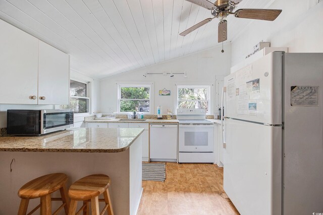 kitchen with light wood-type flooring, white appliances, kitchen peninsula, vaulted ceiling, and white cabinets