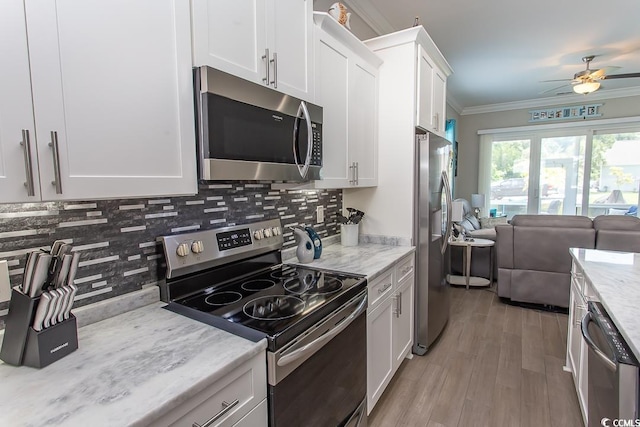 kitchen with ceiling fan, decorative backsplash, ornamental molding, white cabinetry, and stainless steel appliances