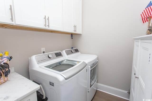 clothes washing area featuring washer and dryer, cabinets, and dark wood-type flooring