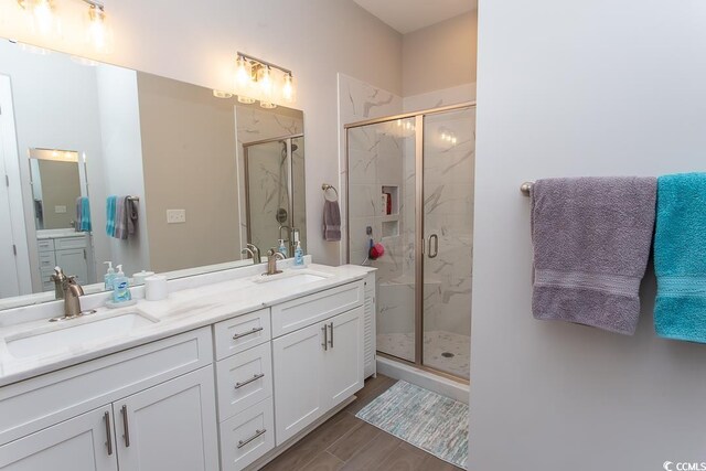 bathroom with an enclosed shower, double sink vanity, and wood-type flooring