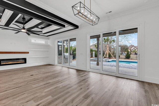 unfurnished living room with hardwood / wood-style flooring, ornamental molding, beam ceiling, and ceiling fan with notable chandelier