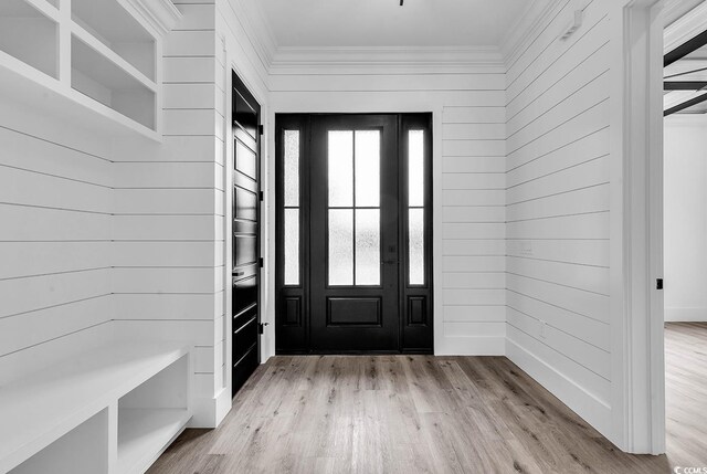 entrance foyer with crown molding, a healthy amount of sunlight, and light wood-type flooring